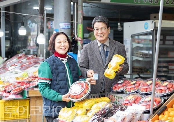 ▲김돈곤(오른쪽) 청양군수가 청양전통시장에서 과일을 고르며 농어촌 기본소득을 사용하는 모습. /사진-청양군