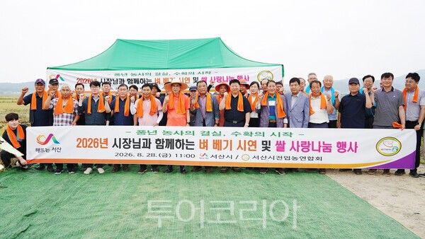 ▲지난 28일 서산시 부석면 지산리 일원에서 열린 벼 베기 시연회에 참석한 이완섭 서산시장과 관계자, (사)한국쌀전업농 서산시연합회 회원들이 단체 기념촬영을 하고 있다. /사진-서산시