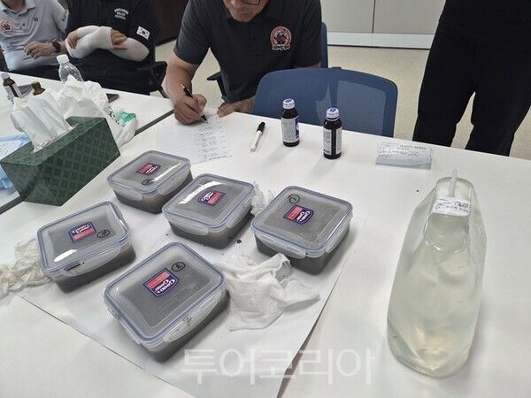 ▲보령머드축제 사용 후 머드의 우수관 방류 논란과 관련해 행사장 배수로에서 채취한 슬러지 시료(앞)와 유출수 시료(오른쪽)가 참석자 입회 아래 봉인되고 있다. /사진-보령시프레스협회