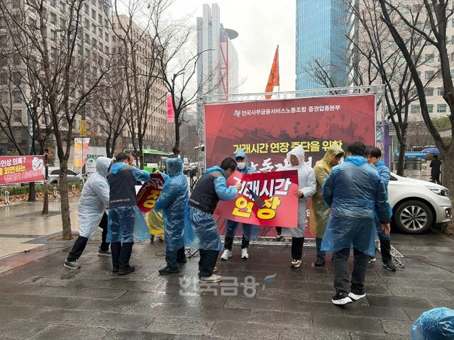 전국사무금융서비스노동조합 증권업종본부는 18일 오전 11시 30분 여의도 한국거래소 앞에서 거래시간 연장 중단을 위한 증권노동자 결의대회를 개최했다. '거래시간 연장'이 적힌 푯말을 격파하는 퍼포먼스를 펼치고 있다. / 사진=한국금융신문(2026.3.18)