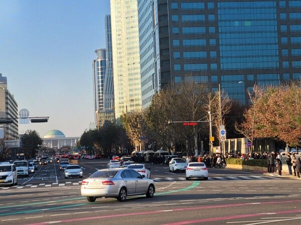 저멀리 국회가 보이고, 촛불집회 참가 시민들이 걸어가고 있다.