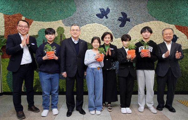 한화 김신연 사장(왼쪽 세번째)이 진잠초 학생들과 함께 공기정화를 위해 한화가 벽면에 조성한 모스월 앞에서 반려 식물을 들고 기념촬영을 하고 있다 [사진=한화](포인트경제)