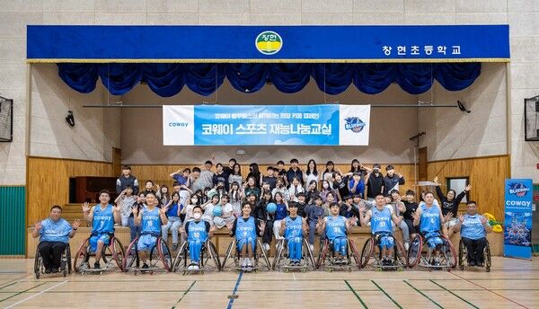 코웨이 블루휠스 휠체어농구단이 남양주 창현초등학교에서 열린 ‘어린이 휠체어농구 체험교실’ 행사 후,&nbsp;참가 학생들과 함께 기념촬영을 하고 있다.
