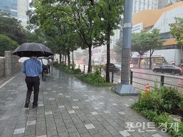 17일 오전 샛강역 부근에서 굵은 비가 쏟아지는 가운데 우산을 쓰고 출근하고 있는 사람들 ⓒ포인트경제