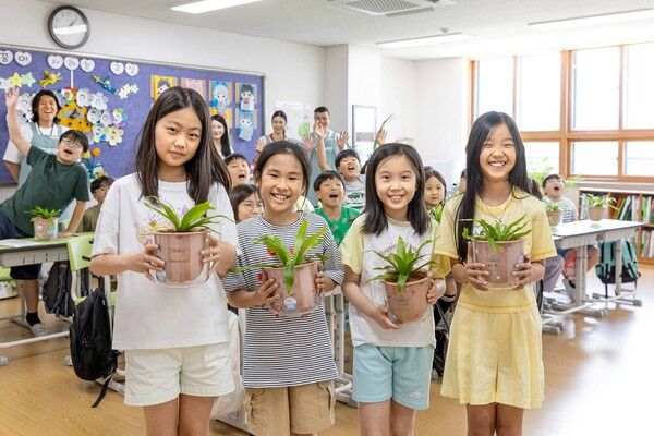 삼일초등학교 학생들이 청정학교 교실숲 식물을 들고 포즈를 취하고 있다. /코웨이 제공
