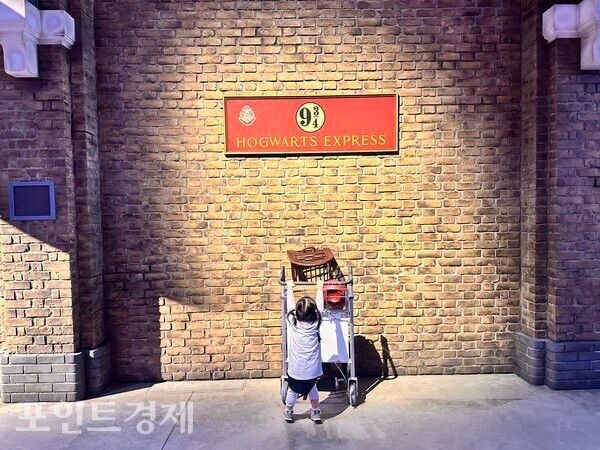 플랫폼 9와 4분의 3을 재현한 포토존 앞에서 어린 관람객이 기념사진을 찍고 있다/사진=박진우 특파원 ⓒ포인트경제