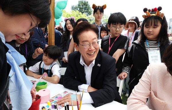 이재명 대통령이 5일 청와대 녹지원에서 열린 2026 어린이날 초청행사에 참석한 어린이들과 함께 손등에 페이스 페인팅을 받고 있다. /사진=뉴시스