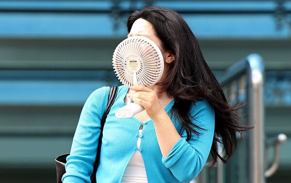 경북 경산과 포항에 첫 폭염중대경보가 발효된 12일 경북 경산시 영남대역 인근에서 한 시민이 손 선풍기를 들고 이동하고 있다. /뉴시스