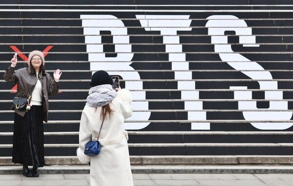 世宗文化会館の階段で、BTSの公演プロモーションを背景に記念撮影する外国人観光客。写真=聯合ニュース