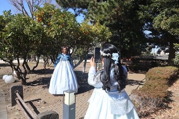 Foreign tourists wearing hanbok take photos together. Photo by Yonhap News .