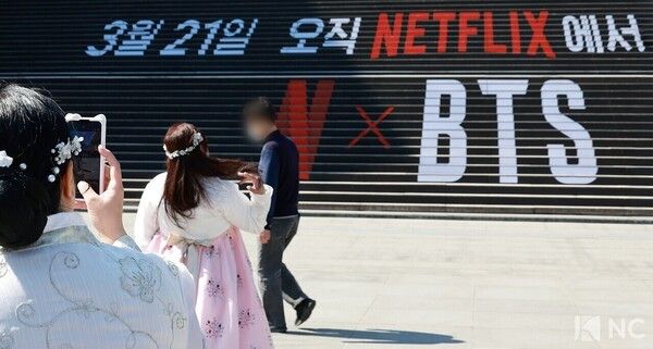 Foreign tourists take commemorative photos in front of a BTS wrapping installation near Gwanghwamun Square. Photo by Kim Gyubin.