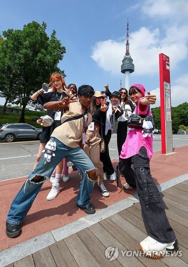 K-culture fans invited to “Korea Invite U” take commemorative photos in front of Namsan Tower in Seoul. Photo by Yonhap News.