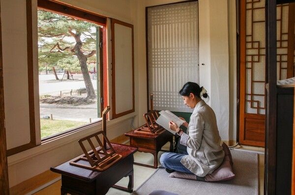 창경궁 영춘헌 봄의 서재 - 정조가 책을 읽던 그 자리에서, 봄날의 워케이션. 2026 봄 궁중문화축전 ‘영춘헌, 봄의 서재’에 참여한 한 관람객이 창경궁 영춘헌 내부에 마련된 1인 업무공간에서 책을 읽고 있다. 영춘헌은 정조가 즐겨 머물며 책을 읽었던 독서 공간으로, 축전 기간에는 활짝 열린 창문 너머로 봄빛이 든 궁궐 풍경을 바라보며 업무와 독서, 사색을 즐기는 ‘집중의 시간’ 공간으로 재탄생했다.. 사진=국가유산진흥원
