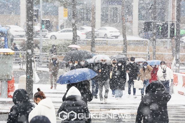 (서울=국제뉴스) 서울과 수도권을 비롯한 중부지방에 대설주의보가 내려진 15일 오후 서울 세종로에서 시민들이 펑펑 내리는 눈을 맞으며 횡단보도를 건너고 있다./사진=이용우기자