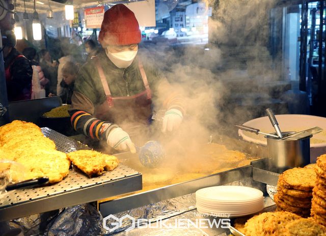 (서울=국제뉴스) 서울 지역에 연일 맹추위가 이어진 가운데 서울 종로구 광장시장 먹자골목에서 음식준비를 하는 상인들 사이로 김이 피어오르고 있다./사진=국제뉴스DB