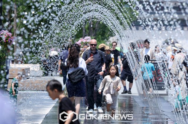 (서울=국제뉴스) 서울 낮 최고기온이 30도를 웃도는 등 여름 날씨를 보인 가운데 아이들과 시민들이 서울 광화문광장 분수터널을 지나며 더위를 식히고 있다./사진=국제뉴스DB