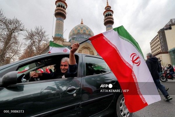 28일 이란 테헤란의 한 모스크 앞에서 정부를 지지하고 미국과 이스라엘의 공습에 항의하는 시위 도중, 한 운전자가 차량에서 이란 국기를 흔들고 있다. 국제뉴스/AFP통신
