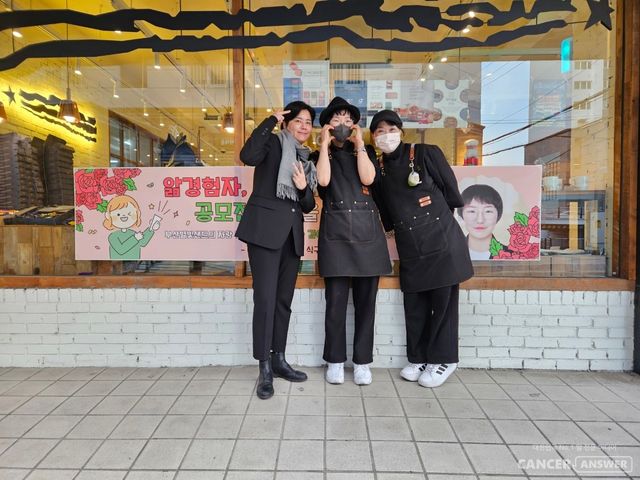 암경험자와 가족들이 모여 만든 캔드림협동조합이 예비사회적기업인 후불제 상조회사 예담라이프(대표 신선철)와 함께 진행하는 ‘앎경험자 나의 이야기’ 공모전 2회 수상자로 난소암 경험자인 김예린 씨가 선정됐다. 김예린 씨(가운데)가 직장인 부산 별빛샌드 베이커리 앞에서 자신의 롤 모델이자 '삶의 원동력'을 준다는 태성당 이나겸 대표(왼쪽), 직장 동료와 함께 당선 기념 촬영을 했다.&nbsp;