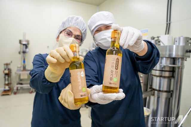 농업회사법인 내포의 직원들이 친환경 토종 들깨를 활용한 들기름 제품을 들고 밝게 웃고 있다