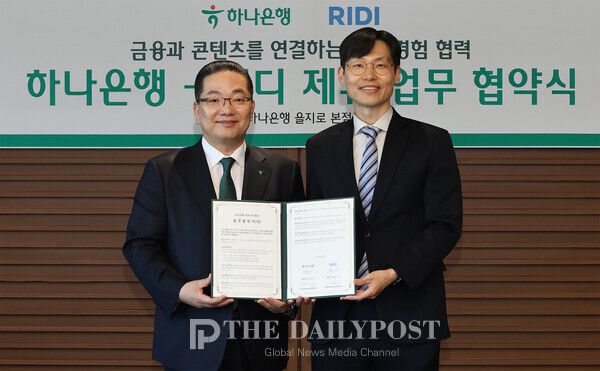 ©데일리포스트=이호성 하나은행장(사진 왼쪽)은 배기식 리디 대표이사(사진 오른쪽)과 함께 협약서를 들고 기념촬영을 하고 있다.