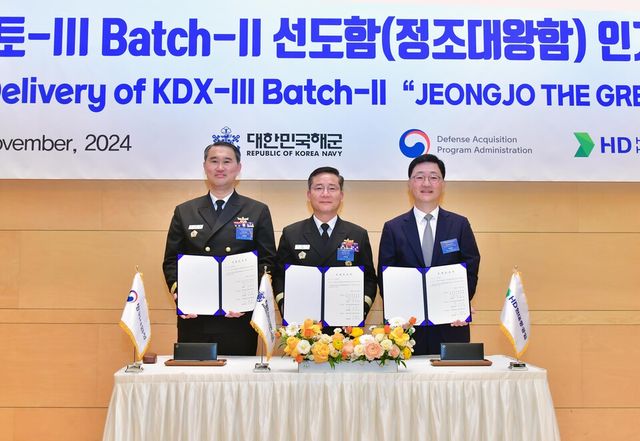 ©AP신문(AP뉴스)/ 이미지 제공 = HD현대 ▲(왼쪽부터) 방위사업청 함정사업부장 신현승 준장, 해군 8전투훈련전단장 박태규 준장, HD현대중공업 특수선사업대표 주원호 부사장이 27일 HD현대중공업 울산 본사 영빈관에서 8200톤급 이지스구축함 정조대왕함의 인계인수서에 서명한 후 기념사진을 촬영하고 있다.