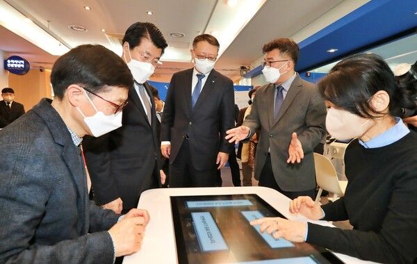 ⓒAP신문(AP뉴스) /&nbsp;우리은행 정진완 은행장(왼쪽 세번째),&nbsp;서강석 송파구청장(왼쪽 두번째)이&nbsp;Woori&nbsp;어르신&nbsp;IT&nbsp;행복배움터 송파점 개소식에 참여해 해피테이블(인지능력개선 디지털기기)에 대한 설명을 듣고 있다.