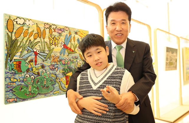 ©AP신문(AP뉴스)/이미지 제공 = 하나금융지주 ▲함영주 하나금융그룹 회장이 17일 하나은행 을지로 본점에서 열린 '제4회 하나 아트버스(Hana Artverse)' 시상식에 참석해 아동·청소년부문 우수상 수상작인 이도원 작가의 '연못마을 개구리와 친구들' 작품 앞에서 이도원 작가와 함께 기념 촬영을 하고 있다.