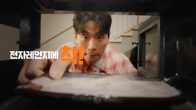 [AP신문 광고평론 No.1297]&nbsp; ​​​​​​​박정민이 냉동 도시락을 전자레인지에 데우고 있다. 사진 아워홈 유튜브 캡처ⓒAP신문(AP뉴스)