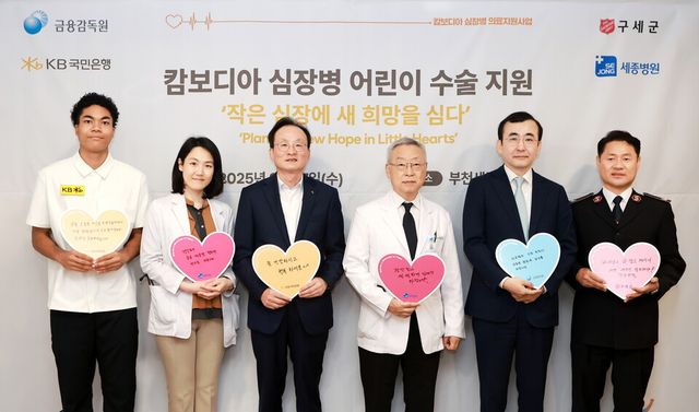 ©AP신문(AP뉴스)/이미지 제공 = KB국민은행 ▲17일 경기도 부천 세종병원에서 열린 병문안 행사에서 (왼쪽부터) 나마디 조엘 진 육상선수, 정현 세종병원 소아청소년과장, 이환주 KB국민은행 은행장, 이명묵 세종병원장, 이세훈 금융감독원 수석부원장,&nbsp; 한세종 구세군 한국군국 서기장관이 기념촬영을 하고 있다.