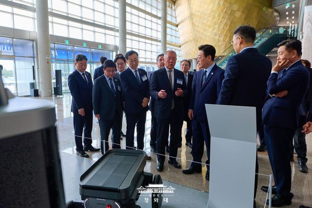 ©AP신문(AP뉴스)/이미지 제공 = 청와대 ▲이재명 대통령이 27일 전북 군산새만금컨벤션센터에서 열린 새만금 로봇·수소·AI 시티 투자협약식에 앞서 정의선 현대차그룹 회장으로부터 자율주행휠로봇(MobED)에 대한 설명을 듣고 있다.