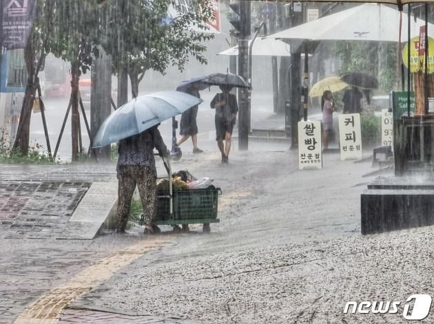 11일 오후 경기 고양 덕양구 수도권 지하철 3호선 화정역 인근에서 한 상인이 우산을 쓴 채 짐을 옮기고 있다. 2023.7.11/뉴스1 ⓒ News1 황덕현 기후환경전문기자