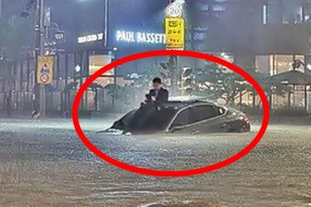 지난 2022년 8월 10일, 서울 강남에 내린 폭우로 도로가 침수되자 제네시스 차 지붕 위로 올라가 구조를 기다린 남성. (온라인 커뮤니티)