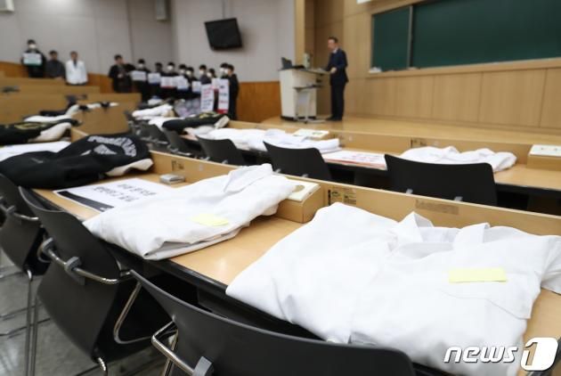 부산대병원·부산대 교수진과 의대생들이 19일 오전 경남 양산시 물금읍 부산대 양산캠퍼스 의과대학에서 의대 정원 확대 사태에 대한 2차 기자회견을 하고 있는 가운데 강의실 책상에 의대생의 가운 등이 놓여 있다. 2024.3.19/뉴스1 ⓒ News1 윤일지 기자