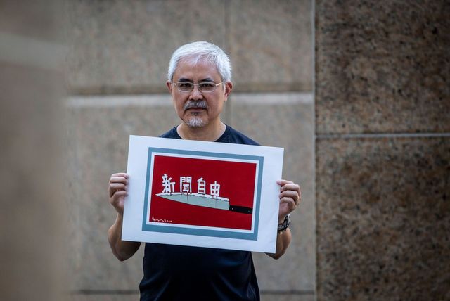 Hong Kong cartoonist Wong Kei-kwan or Zunzi holds up one of his works that said "press freedom"