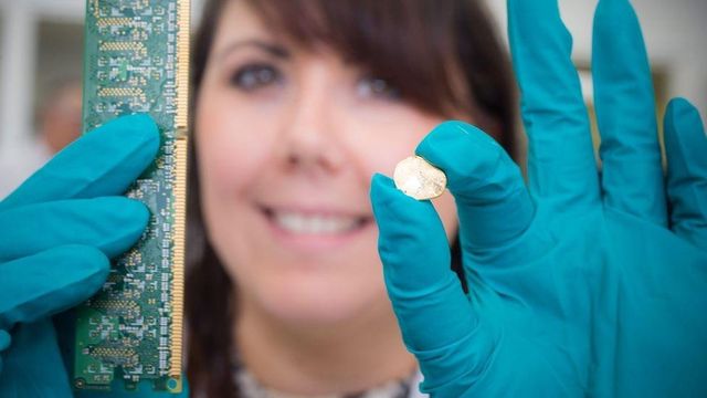 엄지손톱만한 크기의 금덩이와 회로기판을 들고 있는 연구원의 모습