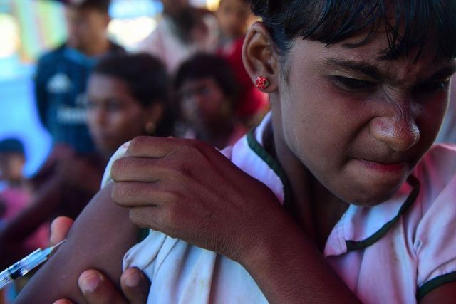 어느 로힝야족 난민 소녀가 팔에 MMR 백신을 맞는 동안 눈을 질끈 감고 있는 모습