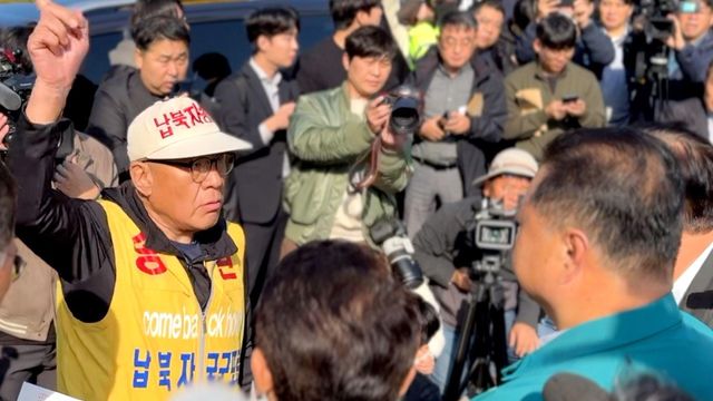 최성룡 납북자피해가족연합회 대표가 김경일 파주시장과 설전을 벌이는 가운데 기자들이 이들을 둘러싸고 있다