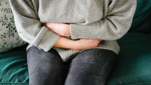 배를 붙잡고 있는 여성