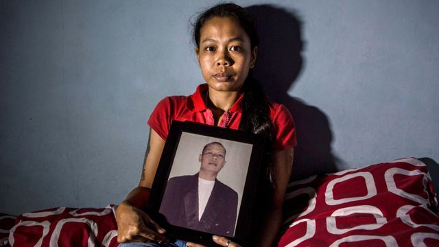 불법 알코올을 마시고 사망한 남편의 사진을 들고 있는 인도네시아 여성