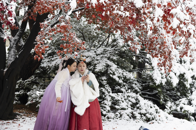 한국 전통 한복을 입은 관광객들이 27일 눈 덮인 서울 경복궁에서 사진을 찍고 있다