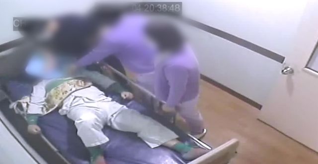 한 의료진이 폐쇄병동에 입원해 있는 환자의 머리를 침구로 누르고 있다 