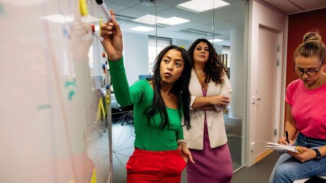 화이트보드 앞에 모여 회의하는 직원들의 모습