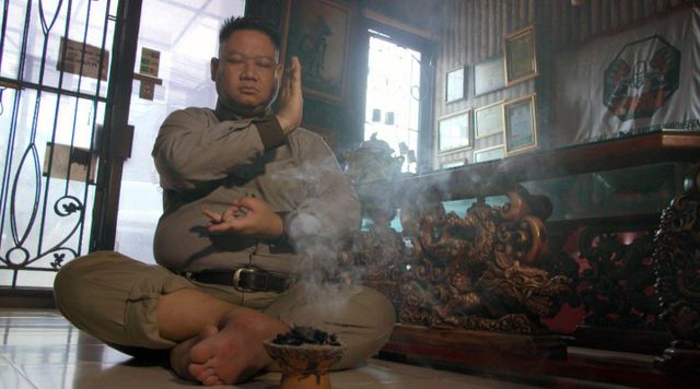 향로 옆에 앉아 눈을 감고 기도하는 쿠스모 키 쿠스모