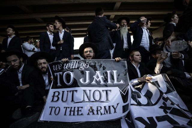 전통 복장을 한 초정통파 유대인들이 병역거부 시위에서 '우리는 감옥에 갈 것이지만 군대에는 가지 않을 것'이라고 적힌 포스터를 들고 있다