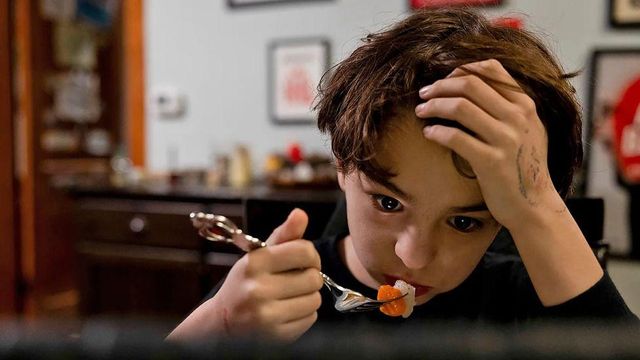 어린아이가 허공을 바라보며 식사를 하고 있다 