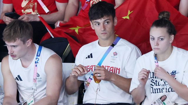 Tom Daley in the middle is seen knitting whilst watching the Women's Synchronised 10m Platform Final on 31 July 2024.