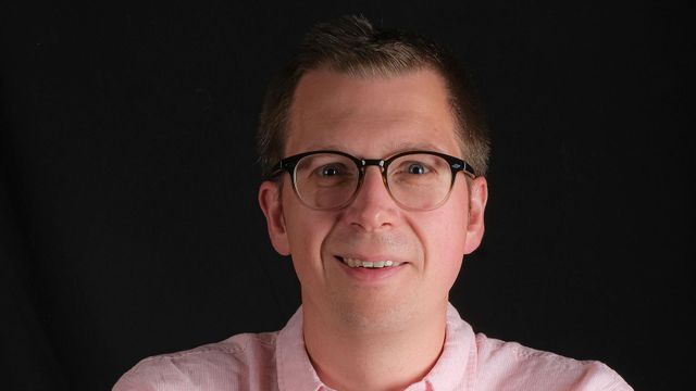 검은색 배경 위 분홍색 셔츠를 입은 제이슨 메이지