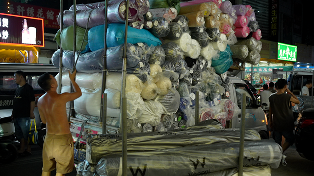 파란색, 흰색, 분홍색 등 다양한 색의 원단을 소형 트럭 뒤에 싣고 있는 남성의 모습