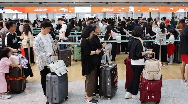 캐리어를 앞에 놓고 출국장에 들어서기 위해 줄을 서 있는 사람들