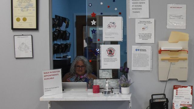 한 직원이 클리닉 접수창구 뒤에 앉아 있으며, 주변 벽에는 각종 안내문이 붙어 있다. 